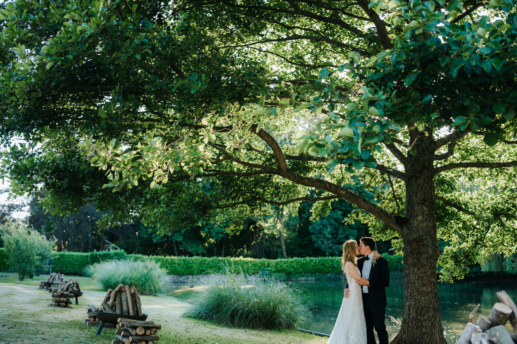 newlyweds under tree by lake 