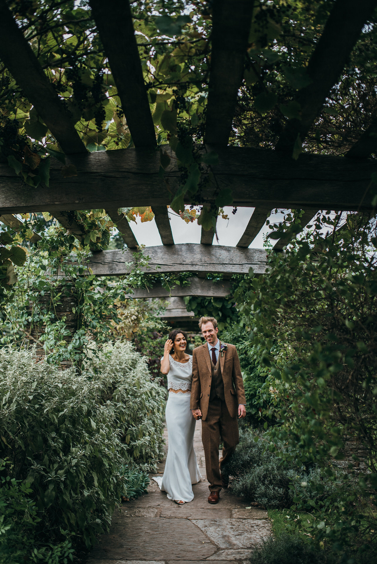 Wedding couple walk under pergola at hestercombe gardens 