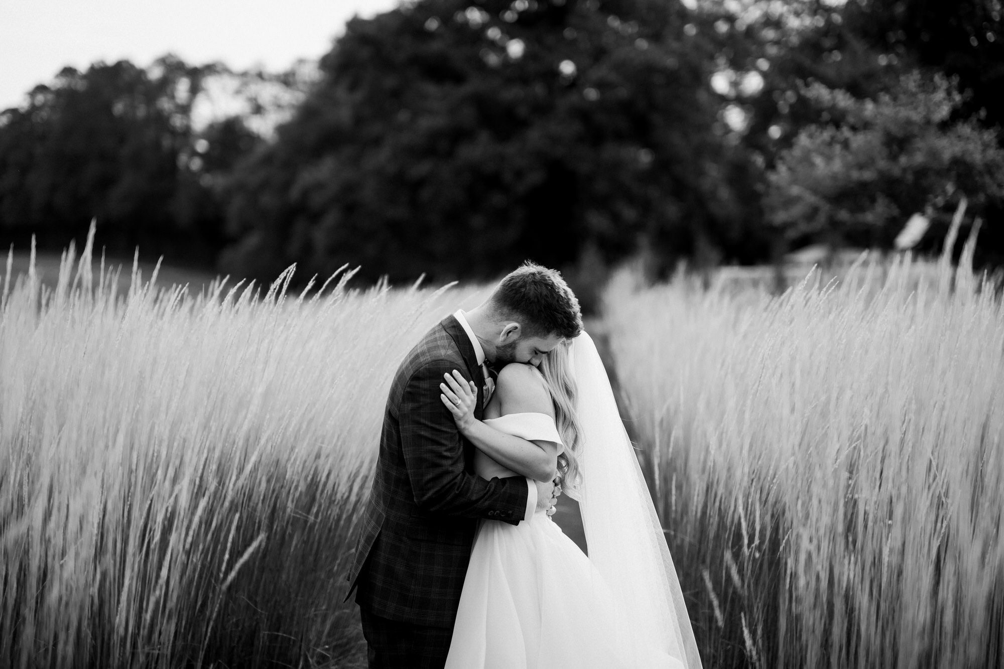 Bride and groom embrace in field at Bury Court 