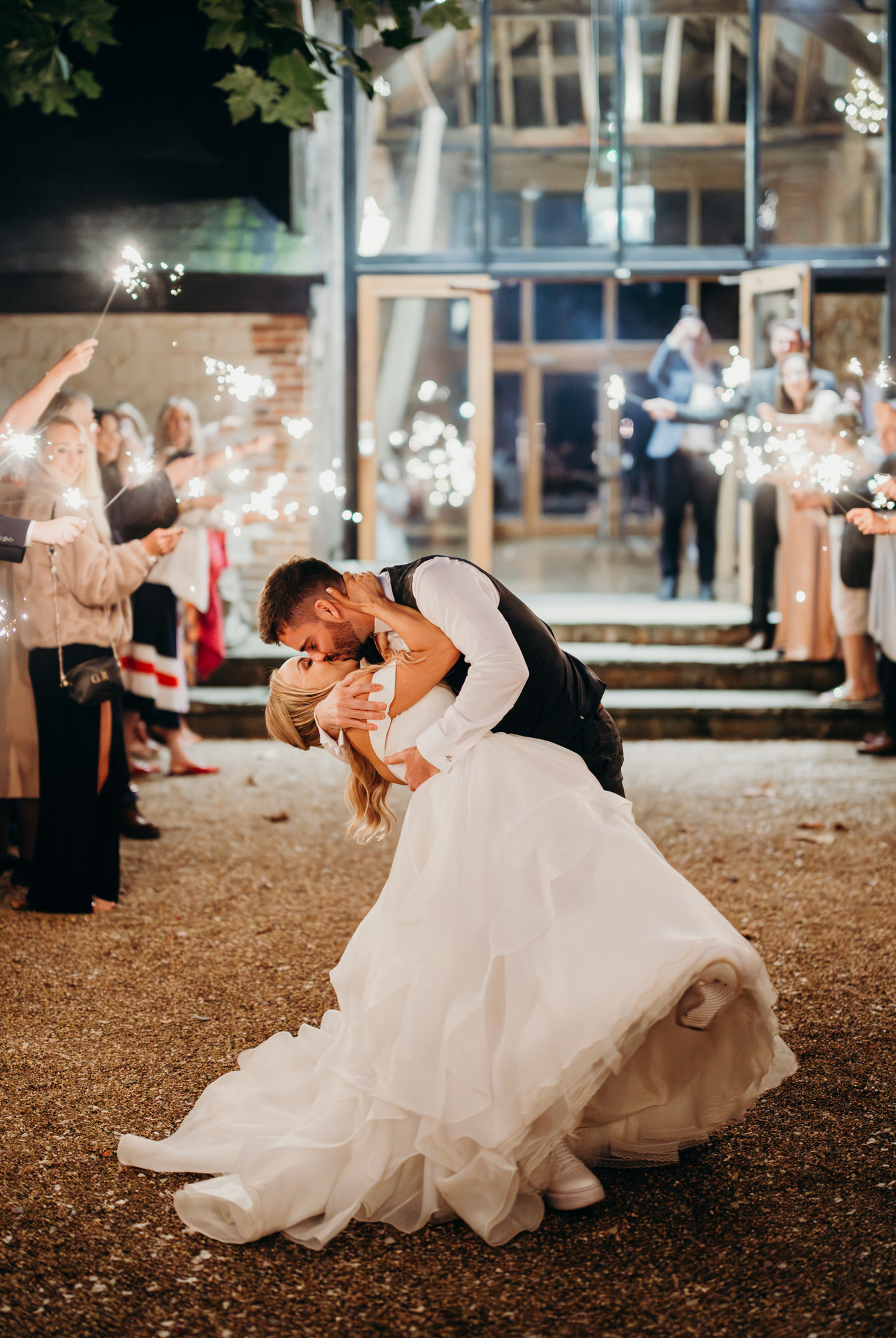 Couple kiss during sparklers at Bury Court wedding  