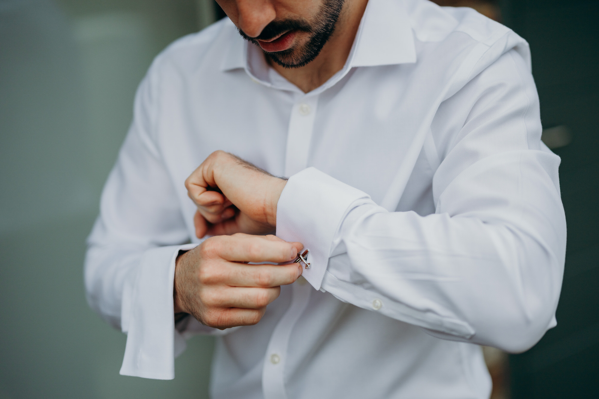 Groom adjusting his suit in the courtyard at Bury Court