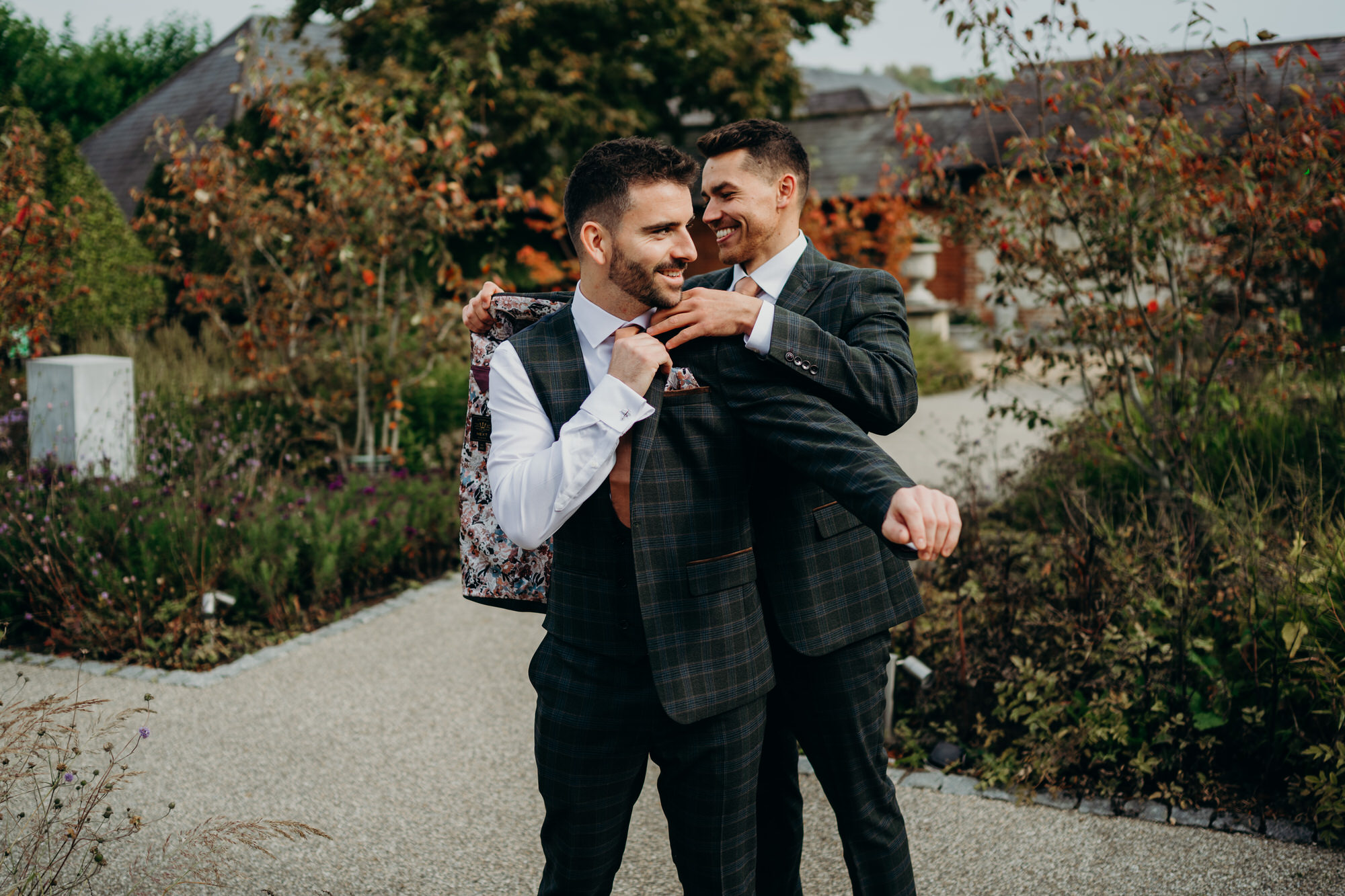 Groom has jacket put on by best man in the courtyard at Bury Court
